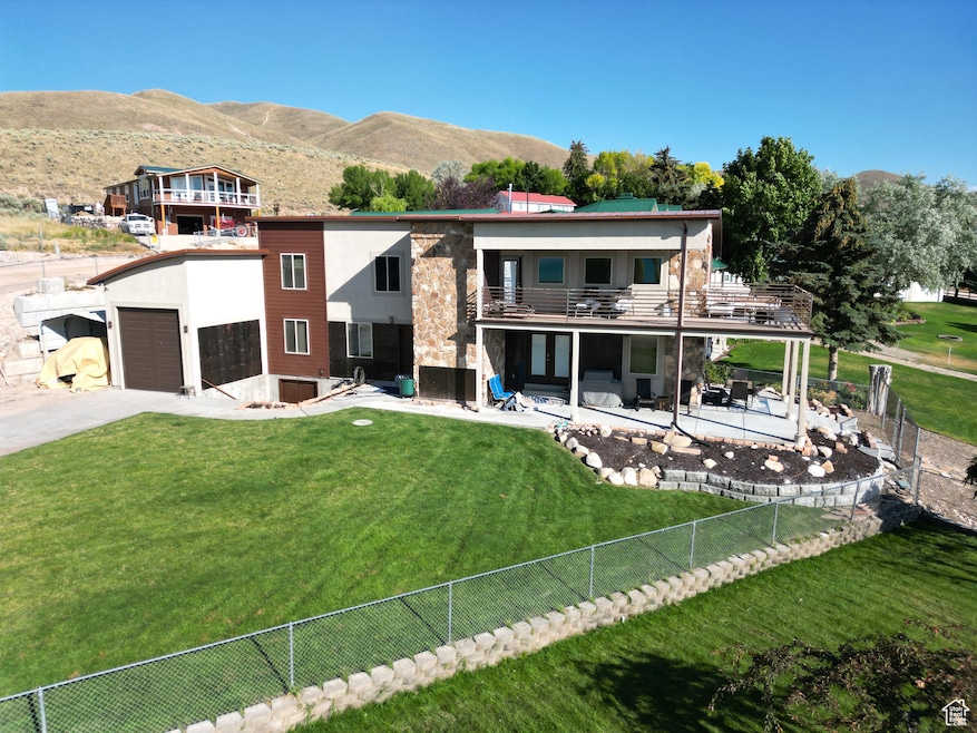 Back of house featuring a fenced backyard, a balcony, a mountain view, a patio area, and concrete driveway