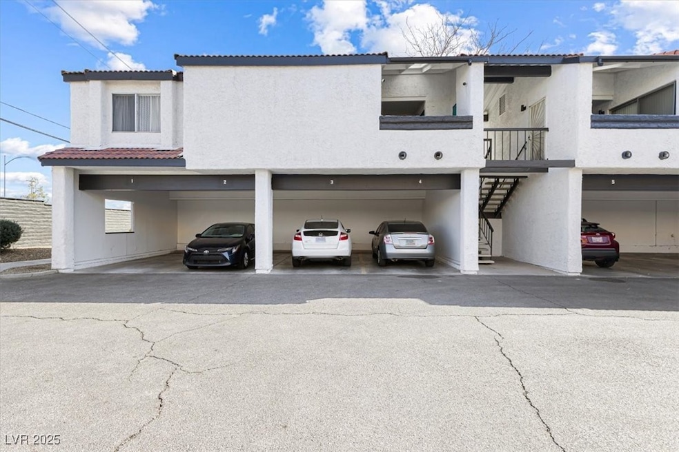 View of property with stairs and covered parking