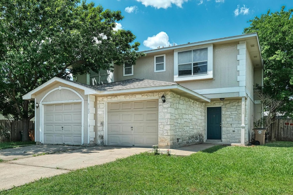View of property featuring stone siding, driveway, and stucco siding
