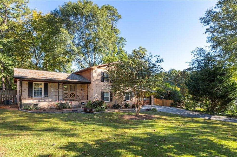 Split level home with covered porch, central AC, and a front lawn