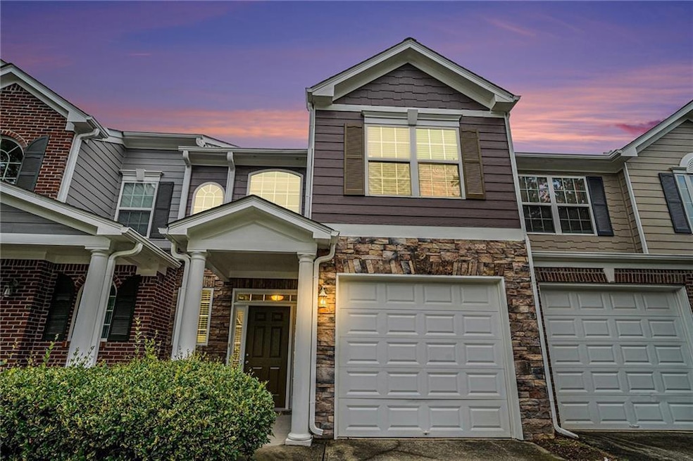 Townhome / multi-family property featuring stone siding, driveway, and an attached garage