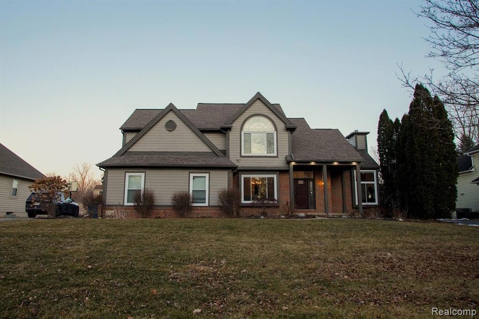 View of front of house with brick siding, a front yard, and a chimney