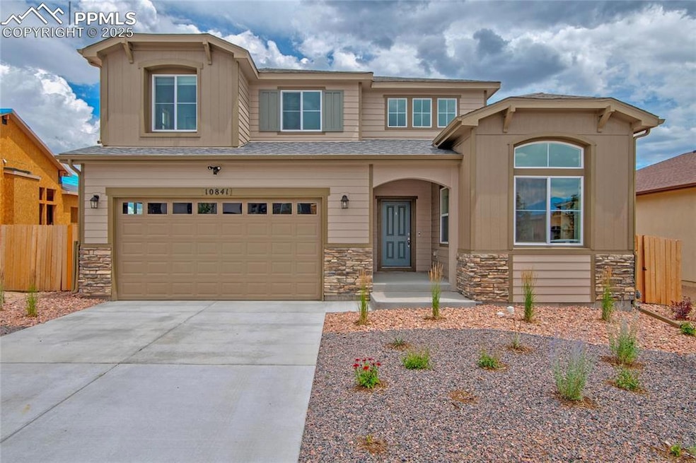 View of front of home featuring stone siding, a garage, driveway, and roof with shingles