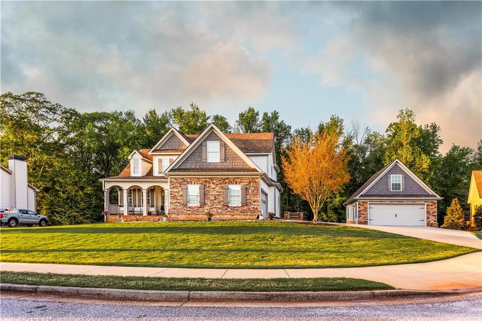 View of front facade with a garage, a porch, stone