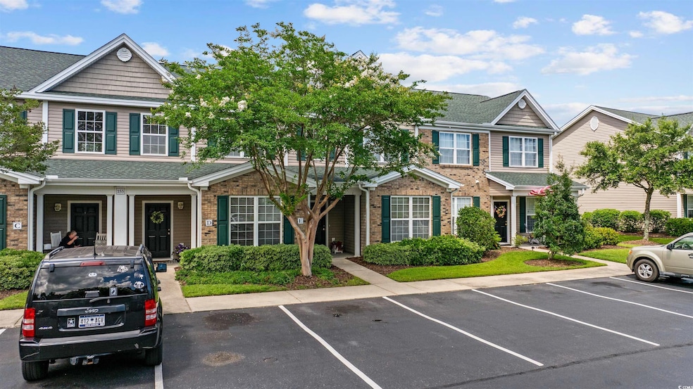 Townhome / multi-family property featuring brick siding, uncovered parking, and roof with shingles