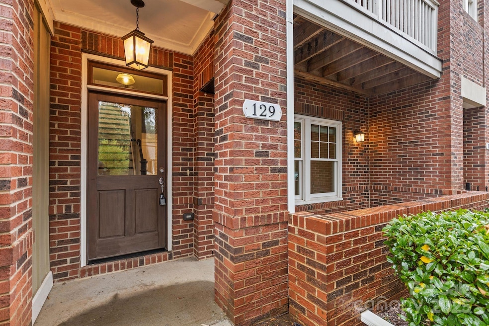 Charming covered entry featuring rich red brickwork, a glass-paneled front door, and elegant outdoor lighting. A cozy front patio enhances curb appeal.