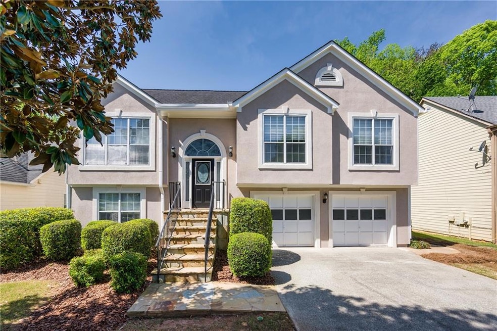 Raised ranch with stucco siding, driveway, and a g