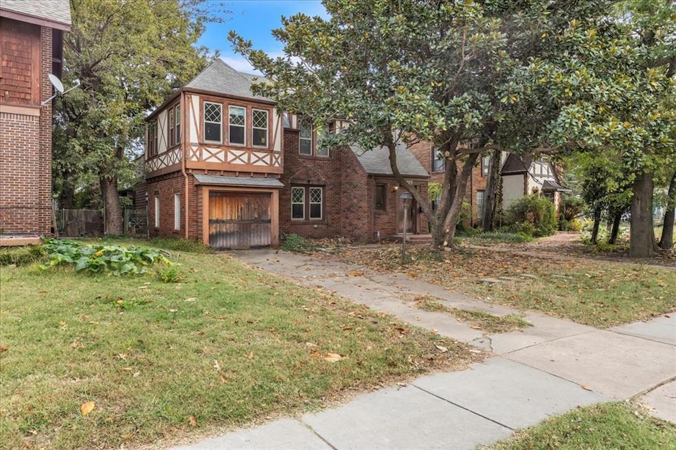 English style home with brick siding, a front yard, a garage, and driveway