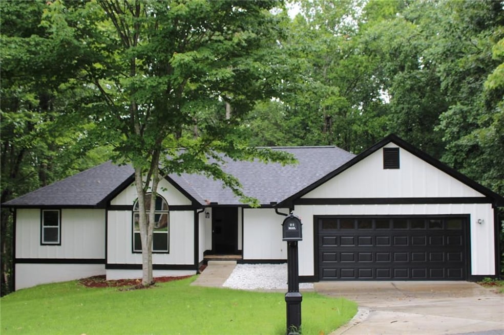 View of front facade featuring driveway, an attached garage, roof with shingles, and a front lawn
