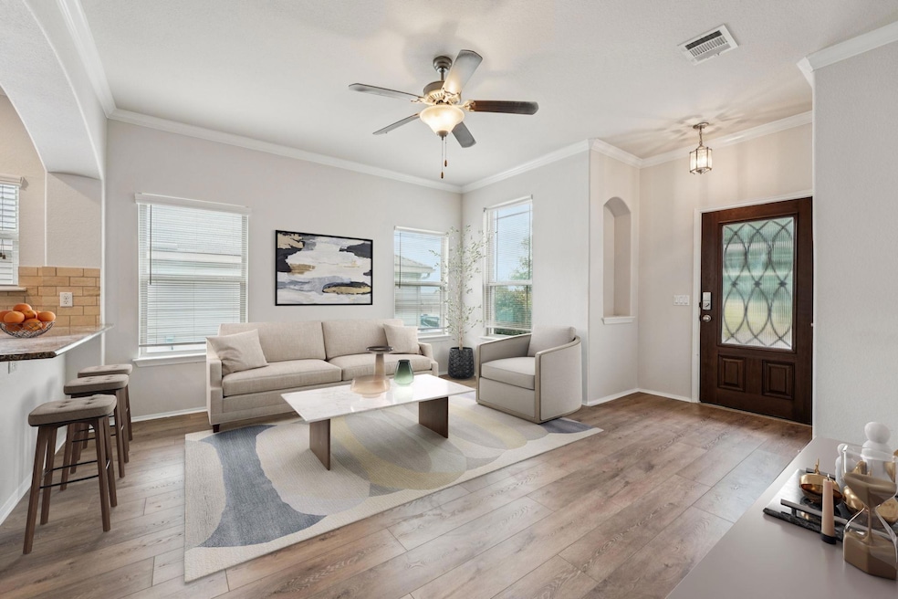 Living area featuring hardwood / wood-style flooring, crown molding, a ceiling fan, baseboards, and arched walkways
