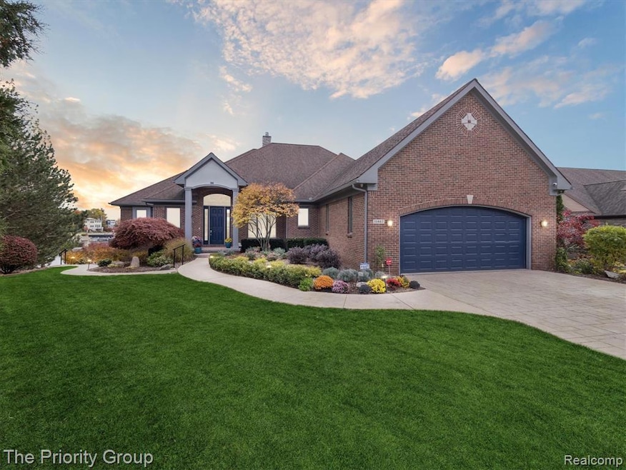 View of front of house with a front yard, decorative driveway, a chimney, and brick siding