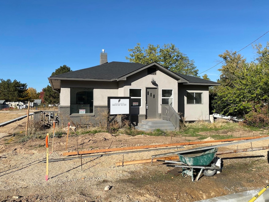 View of front facade featuring stucco siding, a chimney, brick siding, and roof with shingles