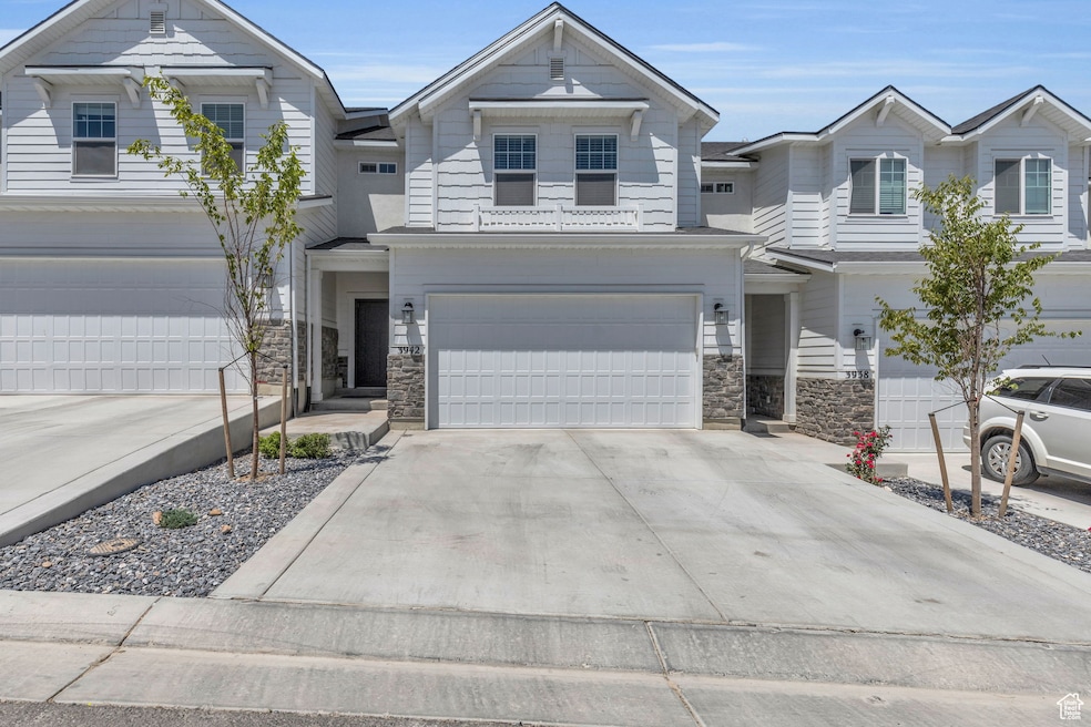 View of front facade with stone siding, driveway, and a garage