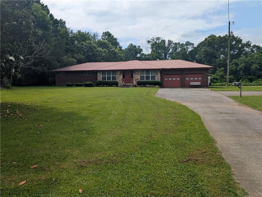 Single story home with a garage, asphalt driveway, and a front lawn