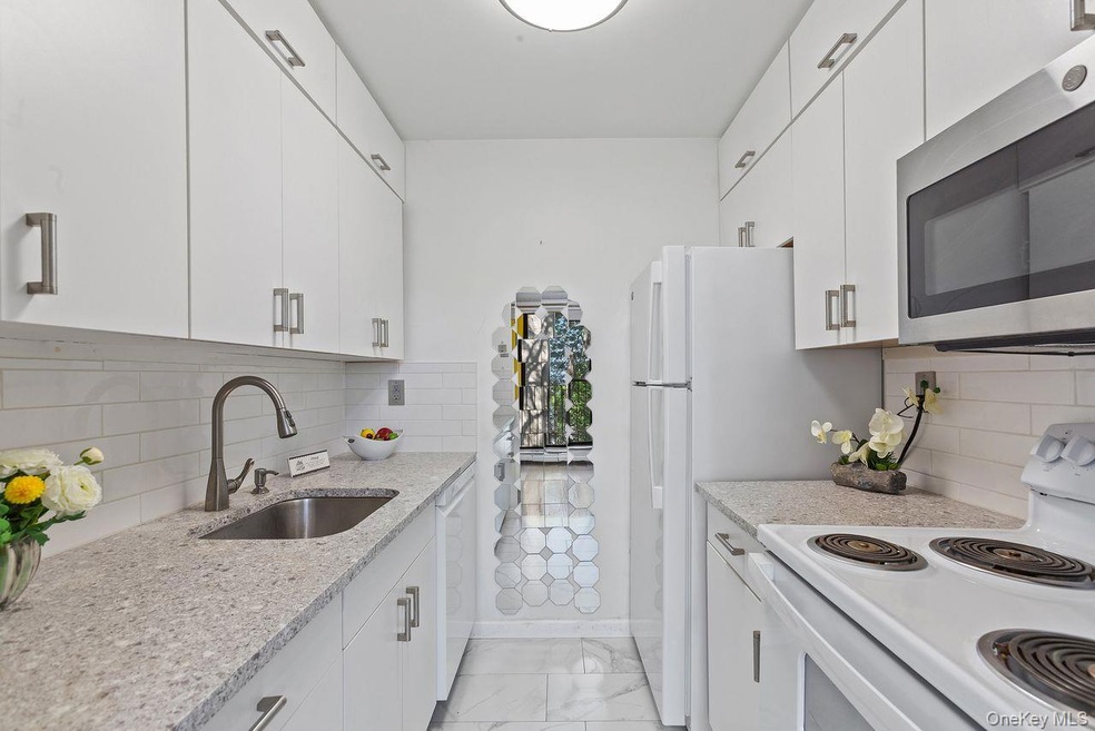 Kitchen featuring white appliances, tasteful backsplash, granite counters, and white cabinetry