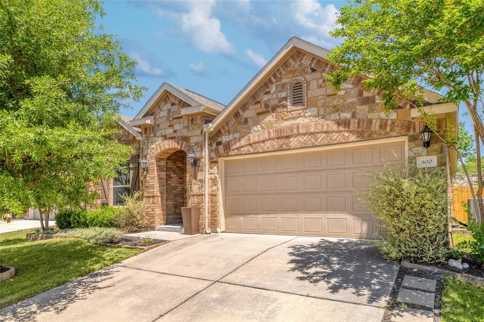 Traditional home featuring driveway, stone siding