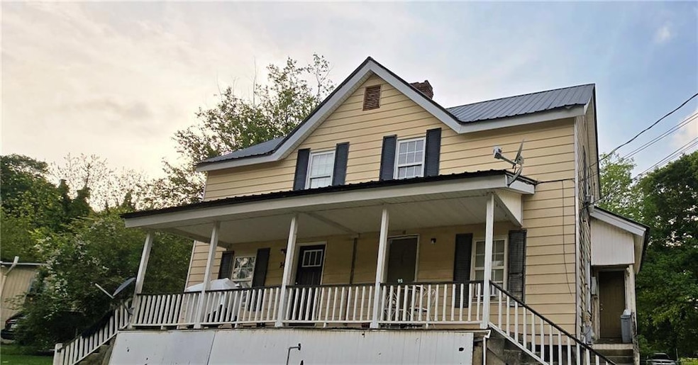 Farmhouse inspired home featuring covered porch, a metal roof, a chimney, and stairs