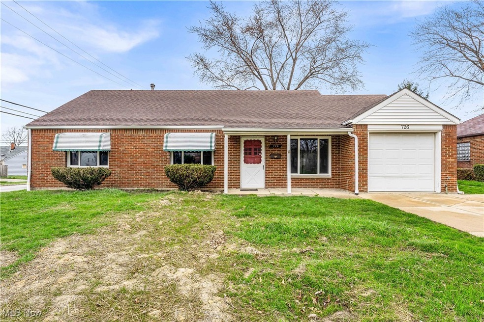 View of front facade featuring a garage, a front lawn, brick siding, and driveway