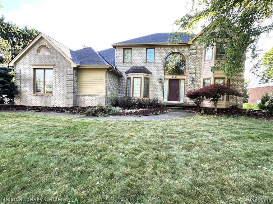 View of front of house with brick siding, a front yard, and roof with shingles