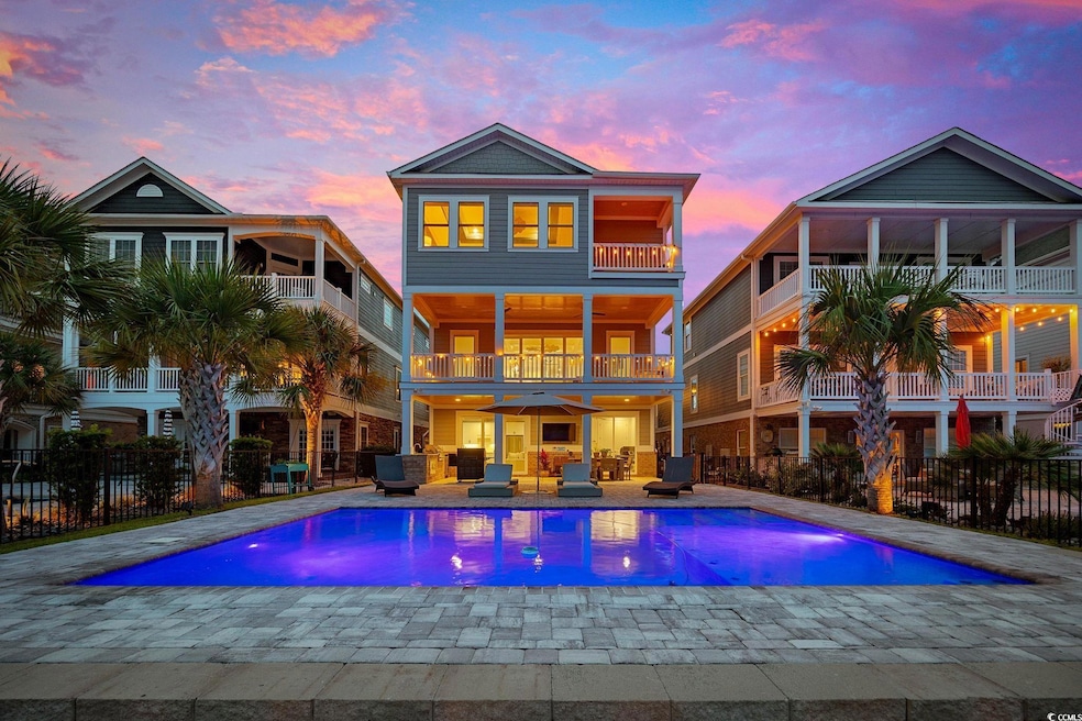 Rear view of the home showcasing multiple balconies, a spacious patio, an outdoor hangout area, and a pool.