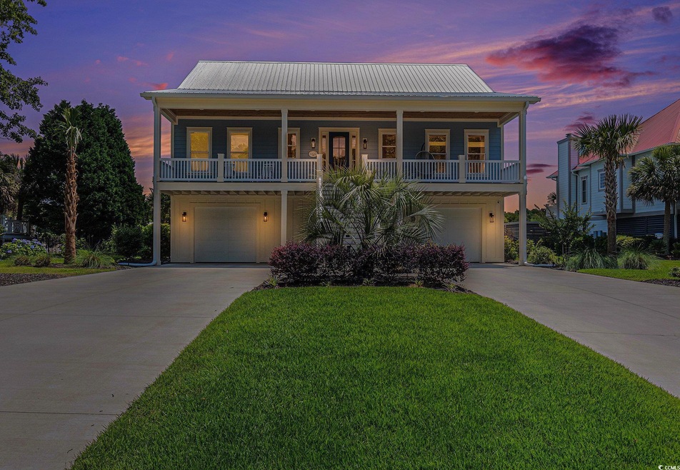 Beach home with driveway, a garage, and metal roof