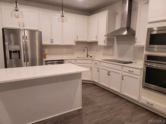Kitchen with dark hardwood / wood-style floors, hanging light fixtures, wall chimney range hood, and stainless steel appliances