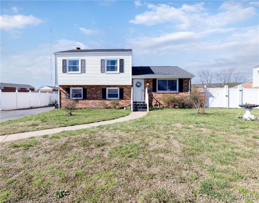 Tri-level home with brick siding, fence, a front l