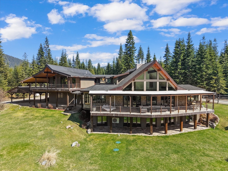 Back of house featuring a wooden deck, a lawn, and a wooded view