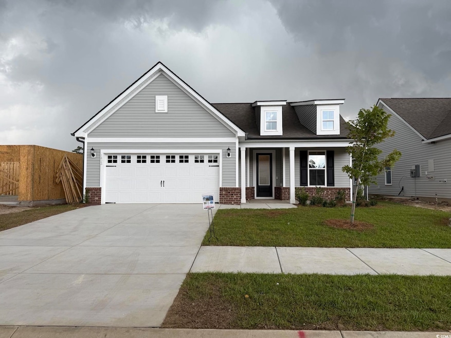 View of front of property with brick siding, driveway, a garage, and a porch