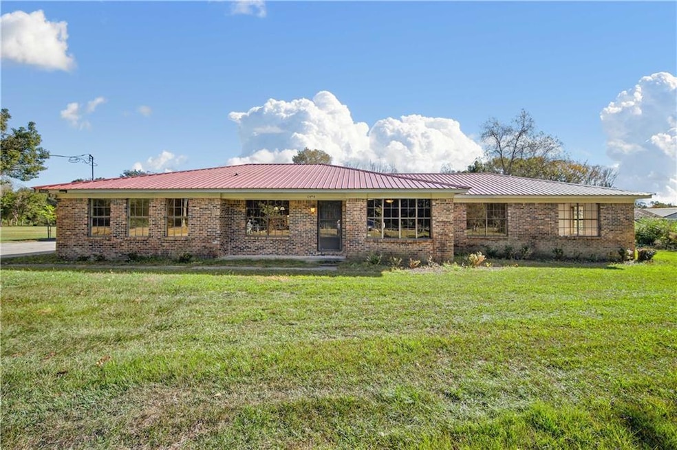 Ranch-style house featuring a front yard, brick siding, and a metal roof