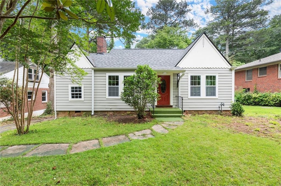 View of front of home with a chimney, a front yard, and roof with shingles