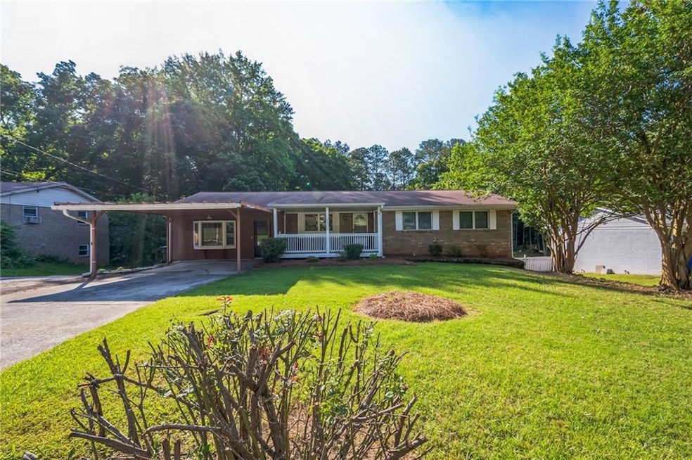 Ranch-style house with driveway, a porch, a front yard, a carport, and brick siding