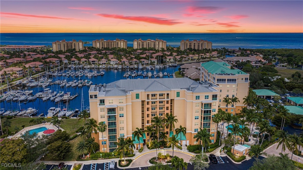 Aerial view at dusk of a view of apartment building / complex, a water view, and view of marina