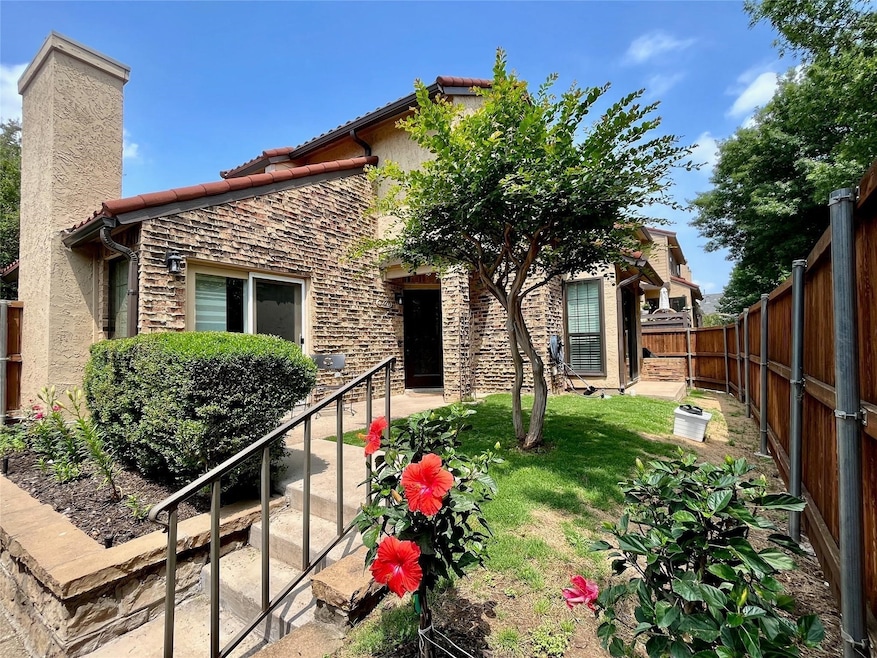 Back of property featuring stone siding, a fenced backyard, a chimney, stucco siding, and a tiled roof