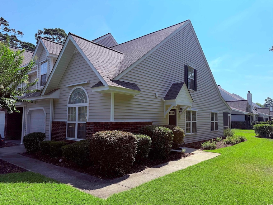 View of front of house featuring roof with shingles, a front yard, and brick siding