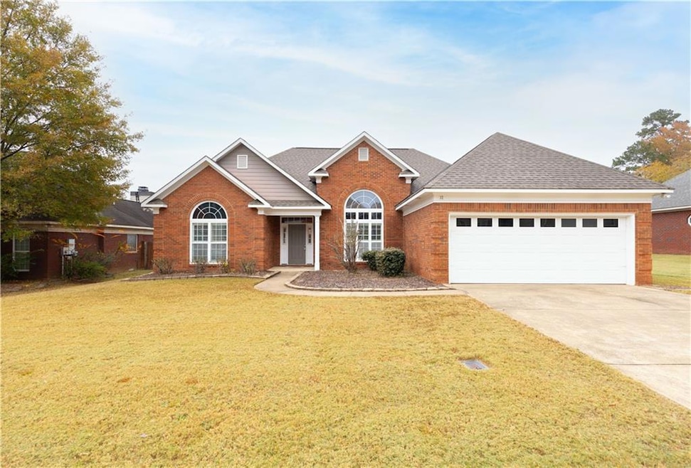 Traditional-style house with concrete driveway, brick siding, a front lawn, and a shingled roof