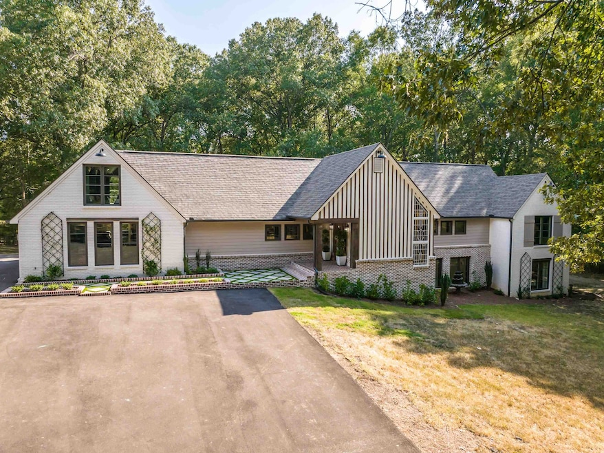 View of front facade featuring brick siding, board and batten siding, roof with shingles, and a front yard