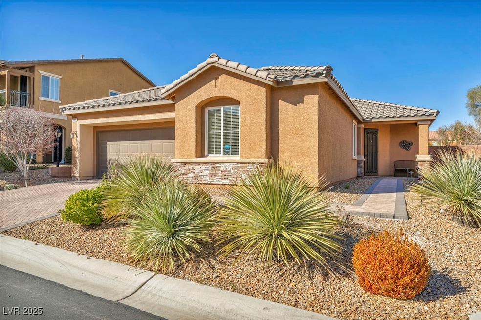 Mediterranean / spanish-style home with stucco siding, a tiled roof, decorative driveway, and a garage