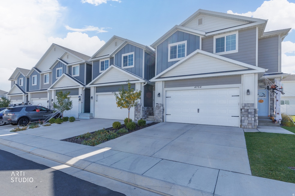 View of front of home featuring board and batten siding, concrete driveway, and stone siding