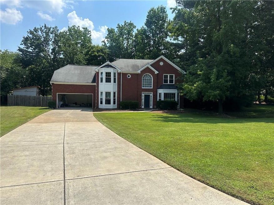 View of front facade with concrete driveway, an attached garage, brick siding, and view of scattered trees