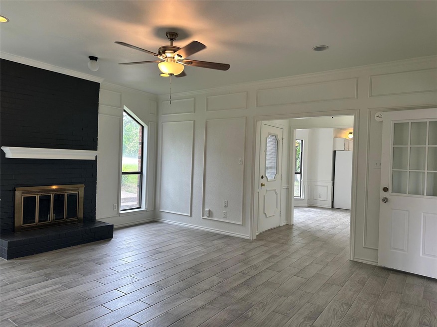 Unfurnished living room featuring ornamental molding, a fireplace, ceiling fan, and light hardwood / wood-style flooring