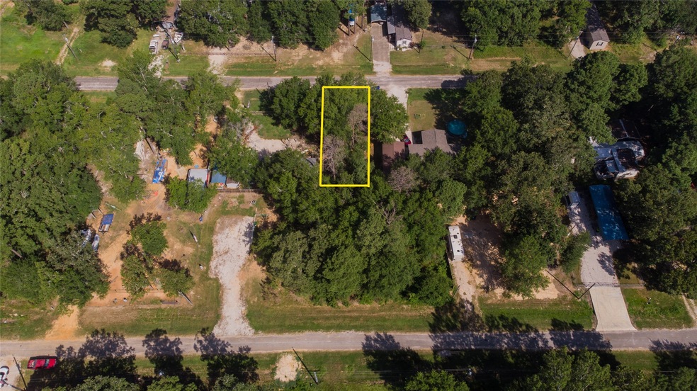This aerial view shows a heavily treed lot with pl