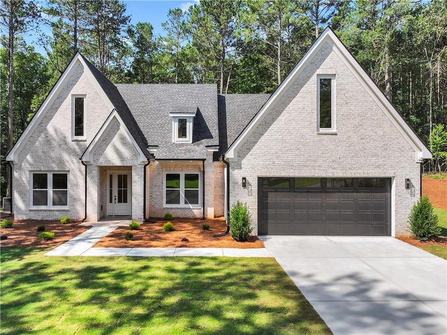 View of front facade featuring a garage, brick siding, driveway, a front lawn, and a shingled roof