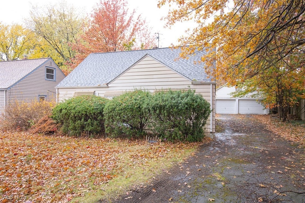 View of side of property featuring roof with shingles, a garage, and an outdoor structure