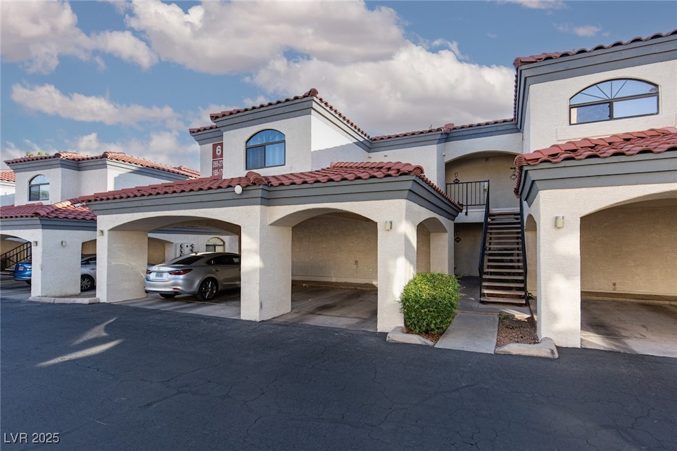 View of front of house featuring a tiled roof, stucco siding, stairs, and covered parking