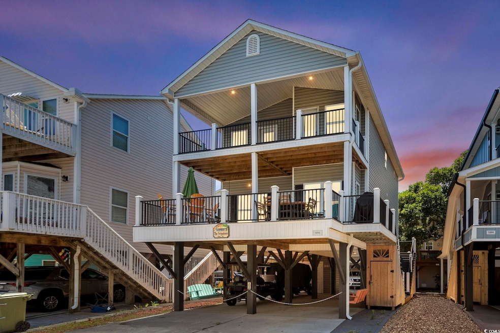 Back of house at dusk with a carport, a balcony, and stairway
