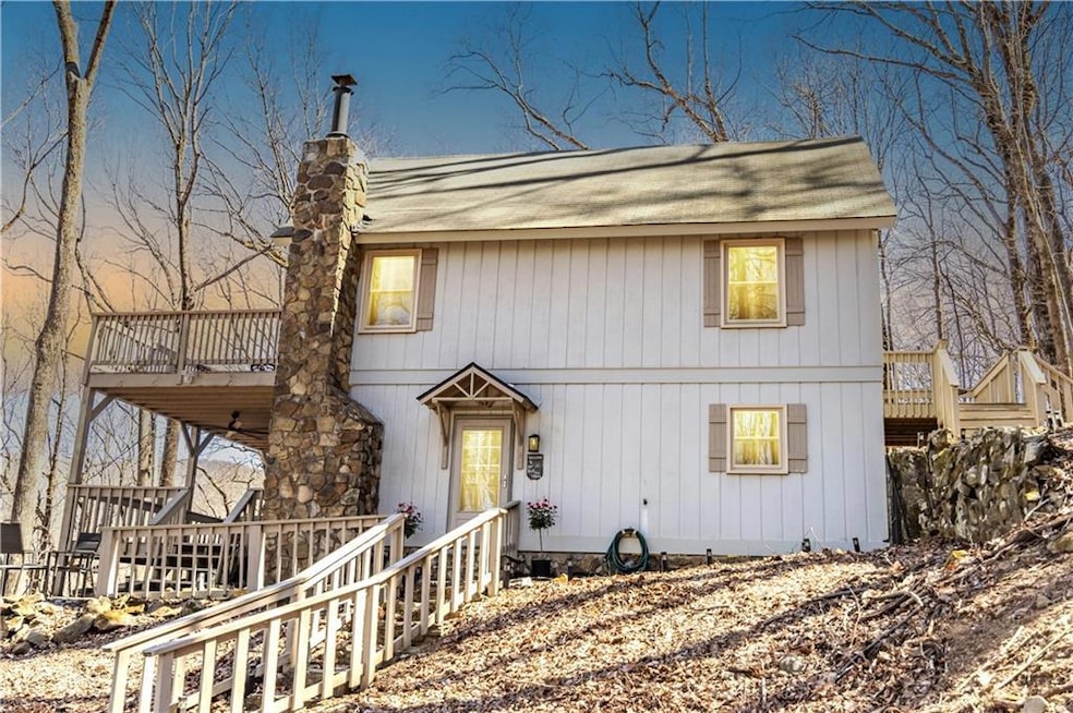 View of front of property with entry steps, a chimney, stairs, a hot tub, and a shingled roof