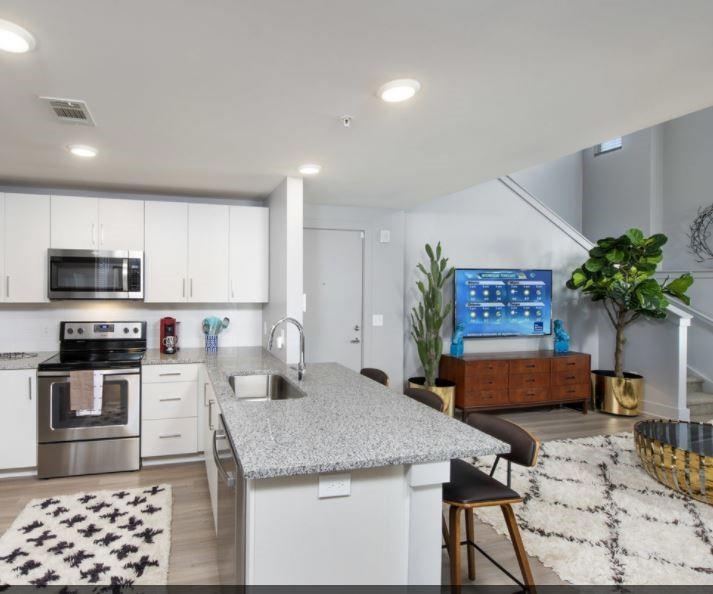 Kitchen with white cabinetry, stainless steel appliances, a kitchen breakfast bar, kitchen peninsula, and sink