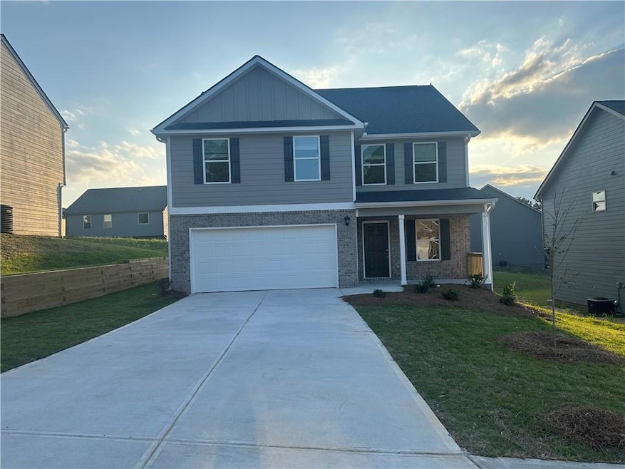 View of front facade featuring a porch, a garage, driveway, and a front lawn