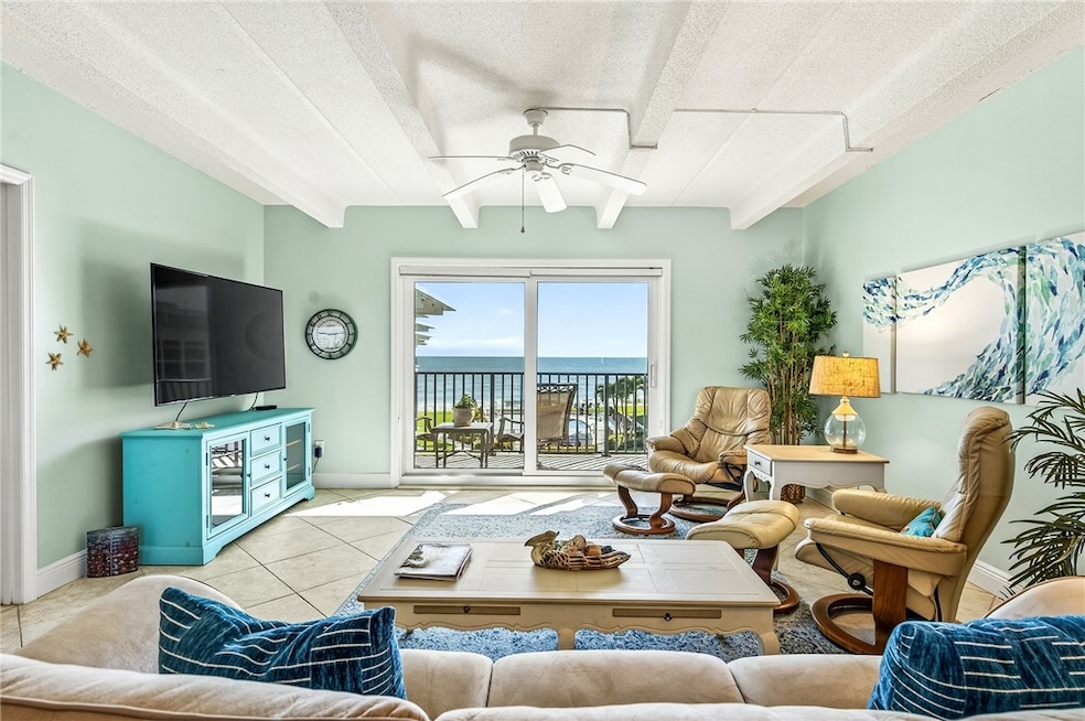 Tiled living area with beam ceiling, and ceiling fan. View of Ocean.